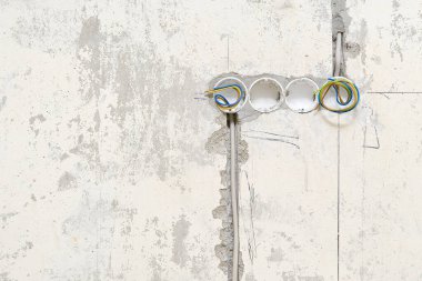 Çukurların altına plastik kutular yerleştirmek için beton bir duvardaki delikler. Soketlerin beton bir duvara ve kablolara yerleştirilmesi.