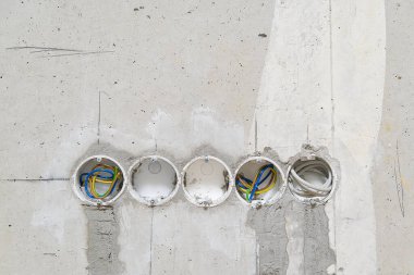 Çukurların altına plastik kutular yerleştirmek için beton bir duvardaki delikler. Soketlerin beton bir duvara ve kablolara yerleştirilmesi.