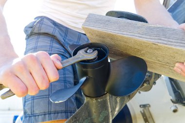 Adam motorun pervanesini değiştiriyor. Teknenin dış motoru tamir ediliyor, vida değiştiriliyor.