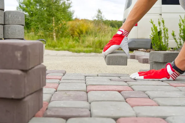 worker laying paving stones. stone pavement, construction worker laying cobblestone rocks on sand.