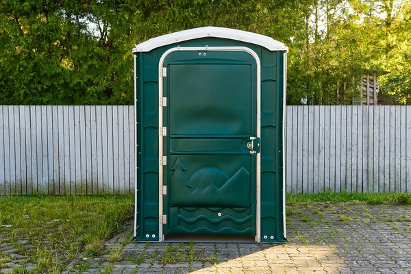 En grön bärbar plast toalett i en park för evenemang. — Stockfoto