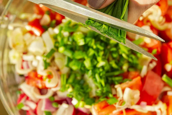 Cortando cebolla verde a ensalada de verduras vegetarianas de verano. cocina casera Ensalada de vitaminas de tomate, pepino, cebolla, aguacate y rábano. —  Fotos de Stock