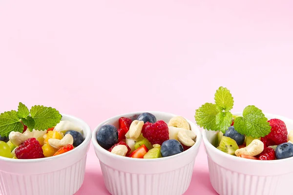 Schaal van gezonde verse fruitsalade op roze achtergrond, zijaanzicht kopieerruimte. — Stockfoto