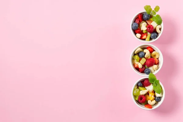 Schaal van gezonde verse fruitsalade op roze achtergrond, bovenaanzicht kopieerruimte. — Stockfoto