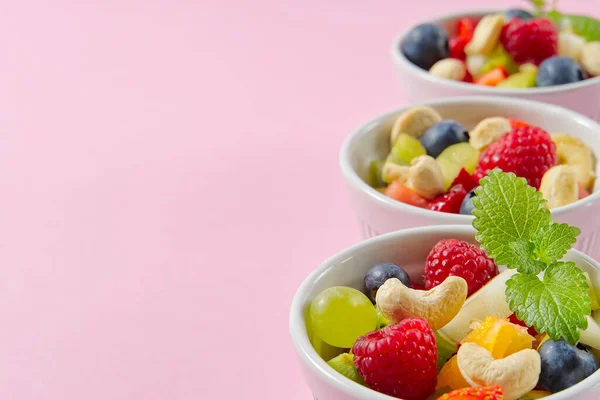 Cuenco de ensalada de frutas frescas saludables sobre fondo rosa, espacio para copiar vista lateral. — Foto de Stock