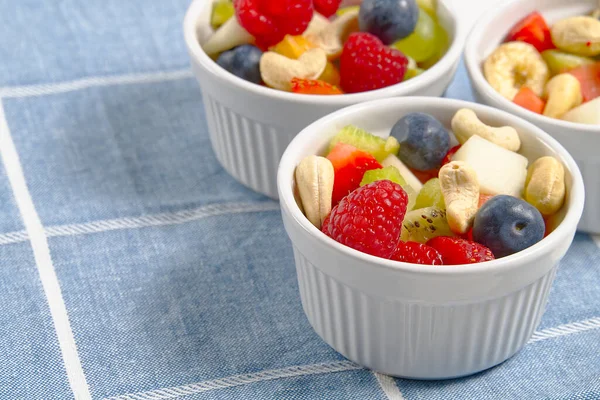 Cuenco de ensalada de frutas frescas saludables sobre fondo de toalla azul lino, espacio de copia de vista superior. — Foto de Stock