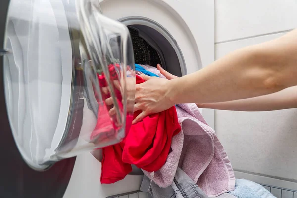 Las manos de mujer sacan la ropa de la lavadora. mujer pone ropa en una lavadora. — Foto de Stock