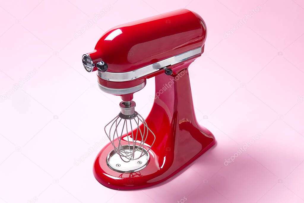 Red kitchen mixer on a pink background.