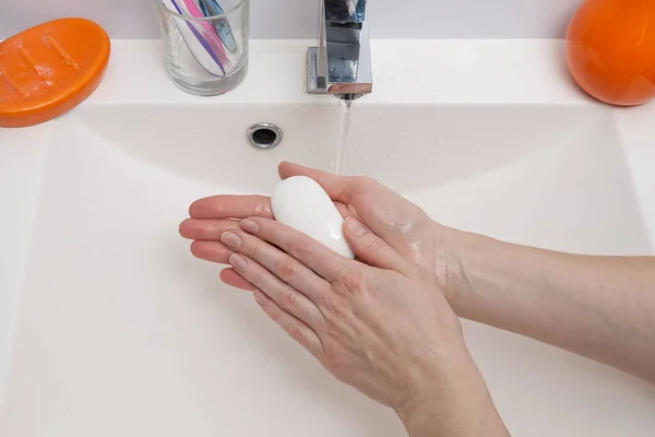 Frau wäscht Hände mit weißer Seife über weißem Waschbecken im Badezimmer, Nahaufnahme. primitiver Covid-Virenschutz. — Stockfoto