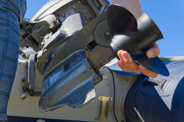 Hombre cambiando hélice en motor fueraborda. Reparación de motor fueraborda para embarcación, sustitución de tornillo. — Foto de Stock