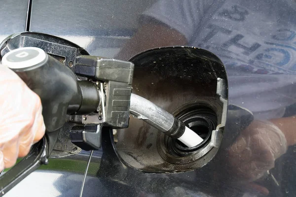 Un hombre repostando un coche negro con diesel en una gasolinera. Boquilla de reabastecimiento cerca y chorro de combustible. — Foto de Stock