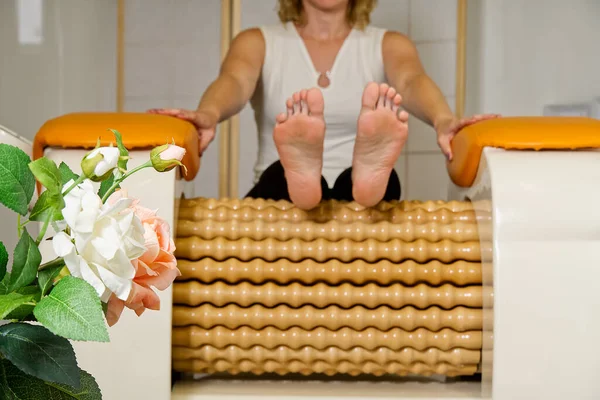 Mujer haciendo masaje para el fémur de la pierna. Roll Massage machine es una forma de dar forma a la figura. Cuidado de la piel, concepto de cuidado corporal. moderno equipo de masaje relax. — Foto de Stock