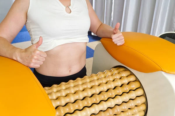 woman making massage for stomach. Roll Massage machine is a way to shape the figure. Skin Care, concept. modern relax massage equipment.
