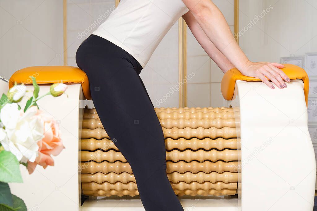 woman making massage for leg femur. Roll Massage machine is a way to shape the figure. Skin Care, body care concept. modern relax massage equipment.