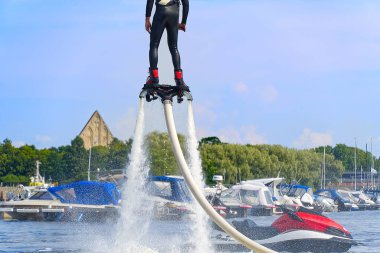 Flyboard 'da eğlenen bir adam. Limandaki nehirde güneşli bir yaz gününde uçağa binmek. Ekstrtrik su aktivitesi uçuş panosu.