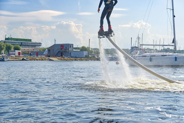 Flyboard 'da eğlenen bir adam. Limandaki nehirde güneşli bir yaz gününde uçağa binmek. Ekstrtrik su aktivitesi uçuş panosu.