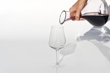 Sommelier beyaz arka planda şarap kadehinden şarap kadehine kadar kırmızı şarap doldurur..