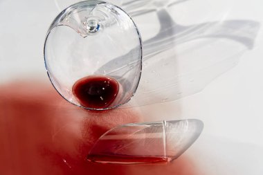 Kırık şarap kadehi ve kırmızı şarap. Aynada kırılmış bir bardak şarap. Beyazda izole edilmiş.