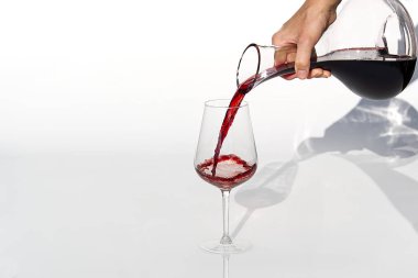 Sommelier beyaz arka planda şarap kadehinden şarap kadehine kadar kırmızı şarap doldurur..