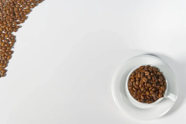 Granos de café en taza blanca, primer plano. Taza de café blanco con semillas de café sobre fondo blanco. Concepto Para el Día Internacional del Café. — Foto de Stock