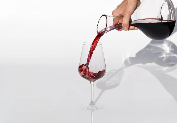 Sommelier nalévá červené víno z karafy na víno na bílém pozadí. — Stock fotografie