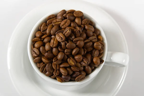 Granos de café en taza blanca, primer plano. Taza de café blanco con semillas de café sobre fondo blanco. Concepto Para el Día Internacional del Café. — Foto de Stock