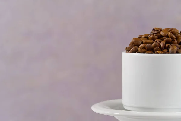 International day of coffee concept. close-up white coffee cup full of coffee beans on old rose Background.