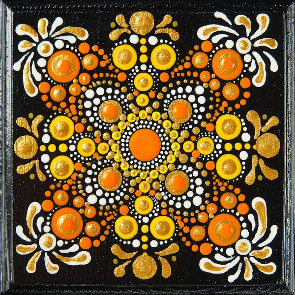 Mandala dot art painting on wood tiles. Beautiful mandala hand painted by colorful dots on black wood. National patterns with acrylic paints, handwork, dot painting. Abstract dotted background.
