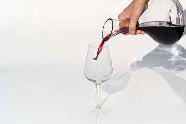 Sommelier beyaz arka planda şarap kadehinden şarap kadehine kadar kırmızı şarap doldurur..