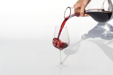 Sommelier beyaz arka planda şarap kadehinden şarap kadehine kadar kırmızı şarap doldurur..