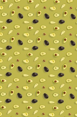 Avokado. Zeytin rengi arka planda izole edilmiş Avokado parçalarından yapılmış arka plan. Taze olgun avokado ve avacado parçalarından oluşan düz bir yer.