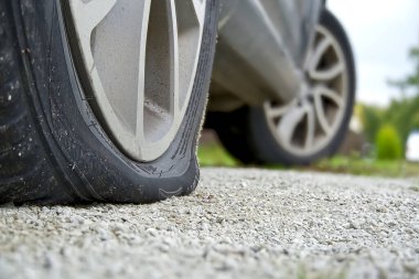 Arabanın arka lastiği patlak, yakın plan. Park yerinde hasar görmüş arka tekerler. Sağ arka kırık gelincik.
