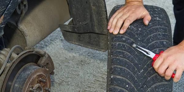 screw in car flat tire. mechanic repair a tire puncture from a nail or screw.