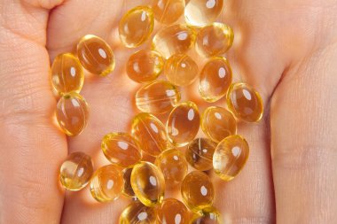 Kadınların elinde D vitamini kapsülleri var. Kapsüllerde Omega-3 vitamini. El kapağı ya da yumuşak şeffaf kapsül hapları Omega 3 ve D vitaminleri bağışıklık için ilaç olarak kullanılıyor.