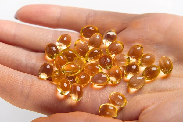 Women hand with gel capsules of D Vitamin . Vitamin Omega-3 fish oil in capsules. hand holding gelcap or softgel transparent capsule pills with omega 3 and vitamins d as medicine for immunity