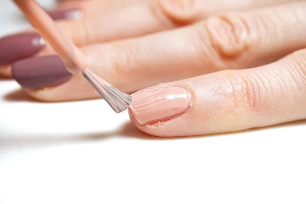 Manicure. Closeup shot of a woman hand polishing nails - manicure. Young caucasian woman receiving a french manicure. Nail technician manicure at nail salon.