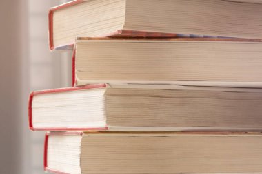 Pencerede yığınla kitap var. Kırmızı kapaklı 4 kalın kitap..