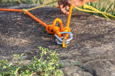 man preparing a rope with carabiner for rappelling on a mountain. clipart