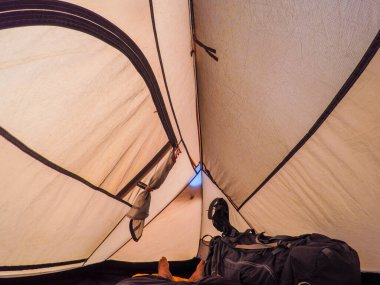 Adam kapalı bir kamp çadırında yatıyor..