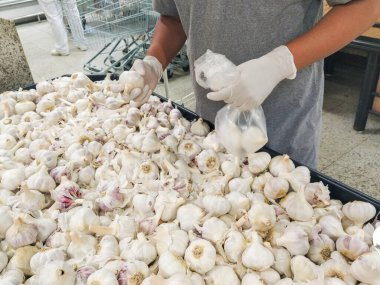 Brezilya 'da koronavirüsten korunmak için eldivenle sarımsak seçen bir adamın siyah elleri..