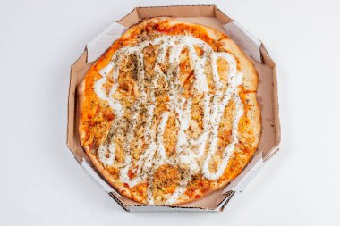 Yuvarlak tavuklu pizza ve beyaz bir masanın üstünde peynir. Brezilya mutfağında çok yaygın bir kombinasyon.