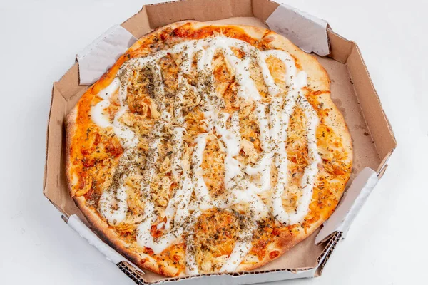 Round chicken pizza with catupiry cheese on a white table. Very common combination in Brazilian cuisine.