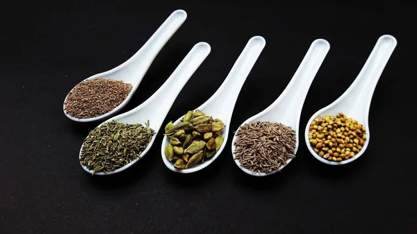 indian spice in spoons isolated on black background