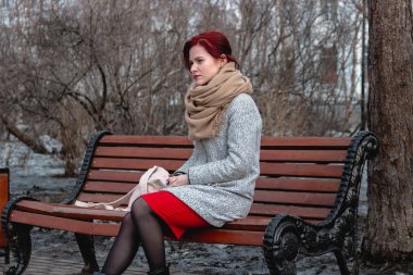 Güzel bej eşarp ve gri ceket parkta bankta oturan poz kırmızı saçlı Pretty genç kadınlar
