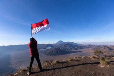 başarılı adam tutarak uzun yürüyüşe çıkan kimse bayrak Endonezya Endonezya seyahat gündoğumu zaman volkan bromo, dağ üstüne uçurum kenarında.