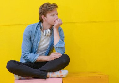 neşeli genç adam sarı kulaklık ile müzik dinlemek 