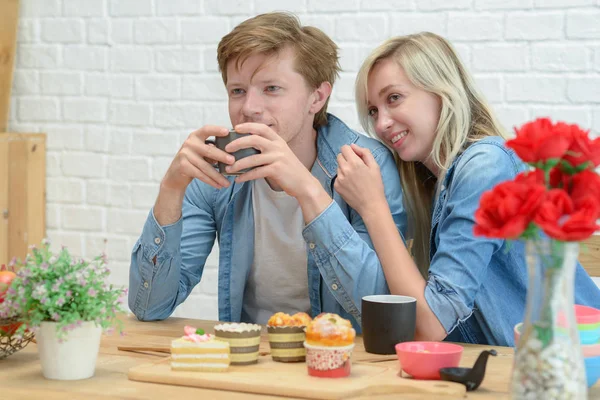 Pareja feliz comiendo café y postre en el kitche blanco —  Fotos de Stock