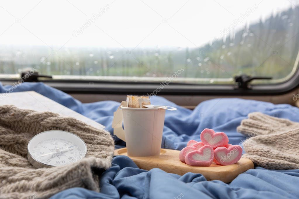 A cup of hot coffee with marshmallow near the window in the cara
