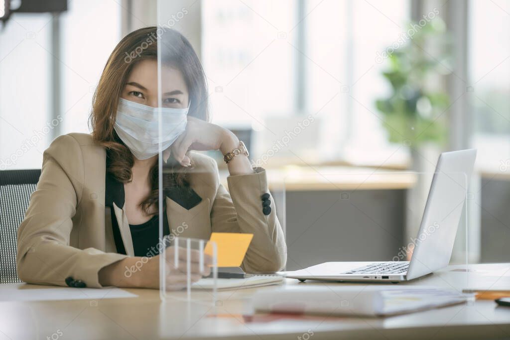 Business woman wearing face mask and using partition on table for protect coronavirus covid-19 pandemic. Social and business distancing new normal lifestyle.