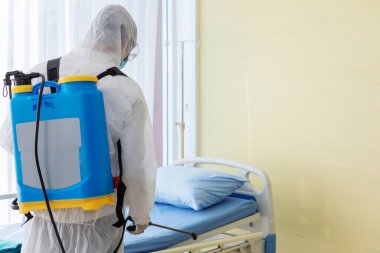 Koronavirüs salgınının ortasında hastane odasında temizlik ve dezenfeksiyon. Dezenfeksiyon çalışmaları için profesyonel ekipler. Salgın için koruyucu giysi ve maskeyi önleme ve kontrol etme..